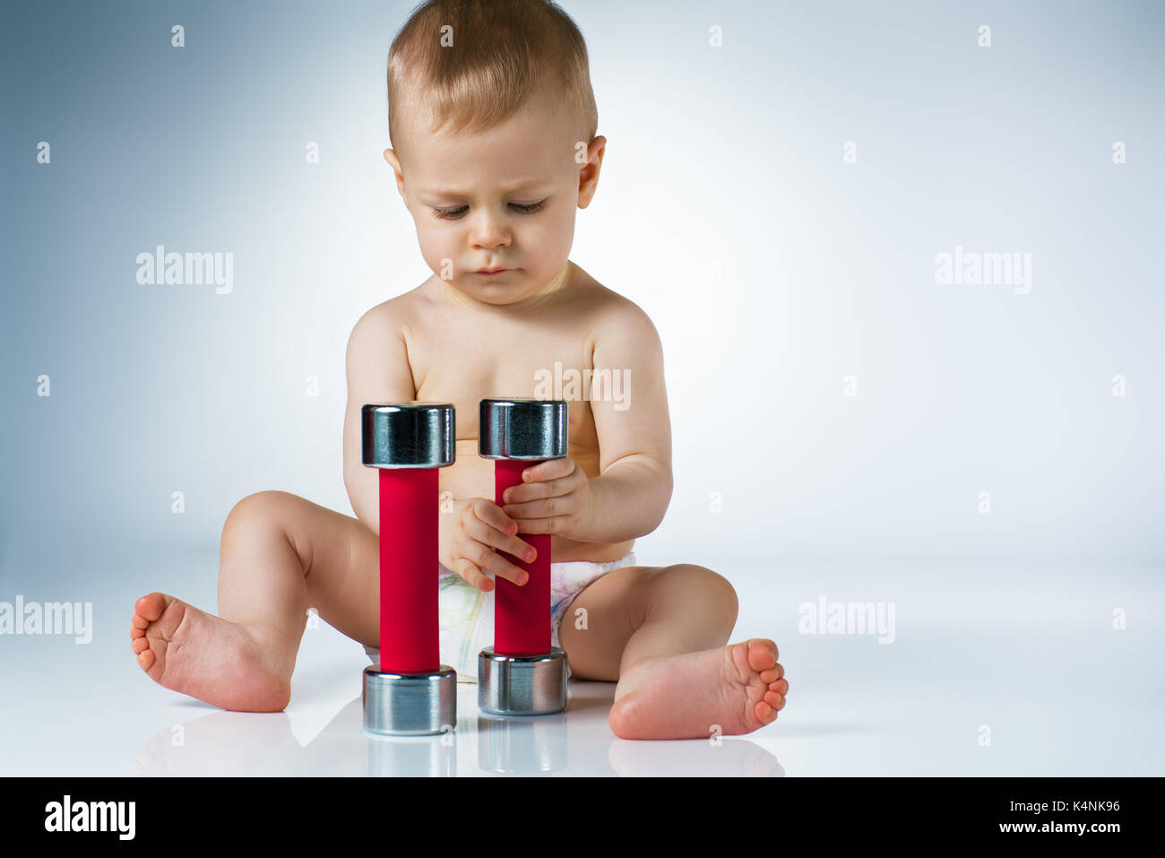 Acht Monate Babysitting und Spielen mit Kurzhanteln auf weißem Hintergrund Stockfoto