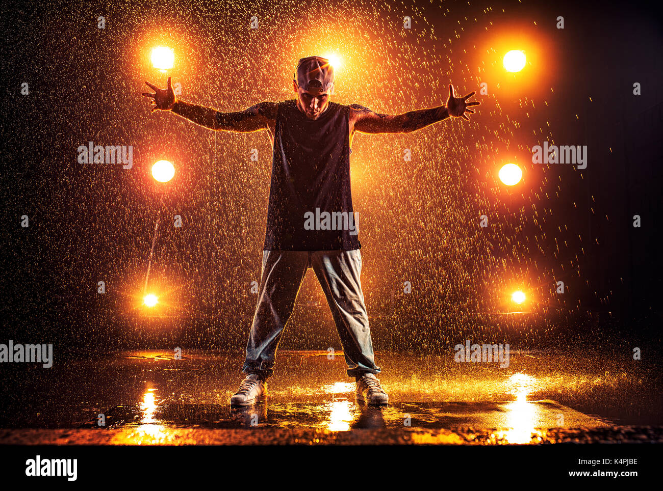 Junger Mann Breakdancer im Club mit Licht und Wasser. Tattoo am Körper. Stockfoto