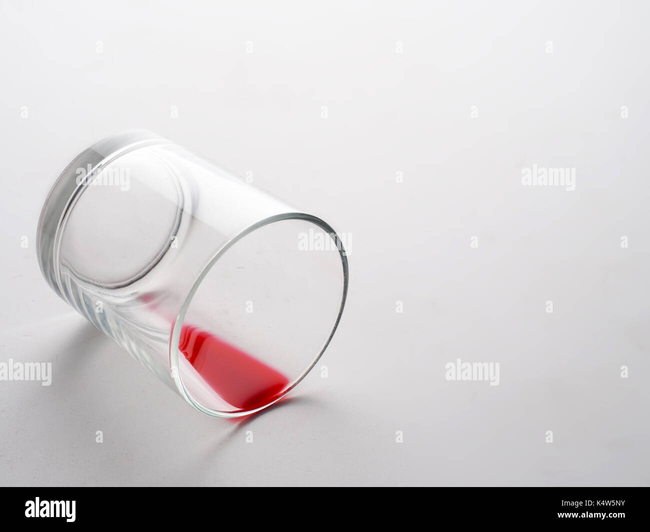 Glas mit roter Flüssigkeit wie Blut. Schmerzen oder Verlust Metapher. Stockfoto