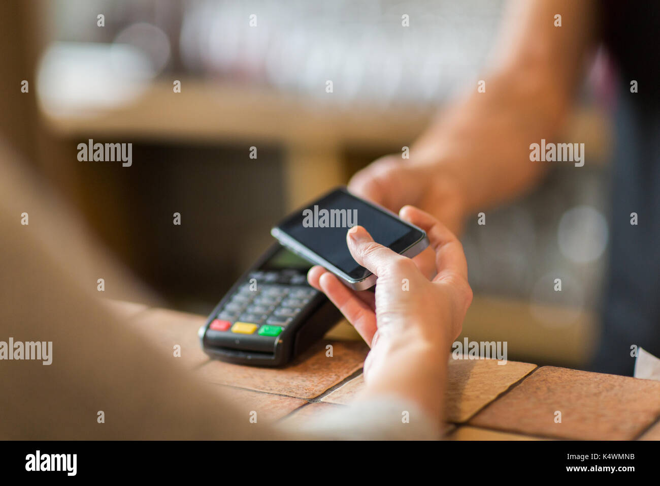 Hände mit Payment Terminal und Smartphone in der Bar Stockfoto