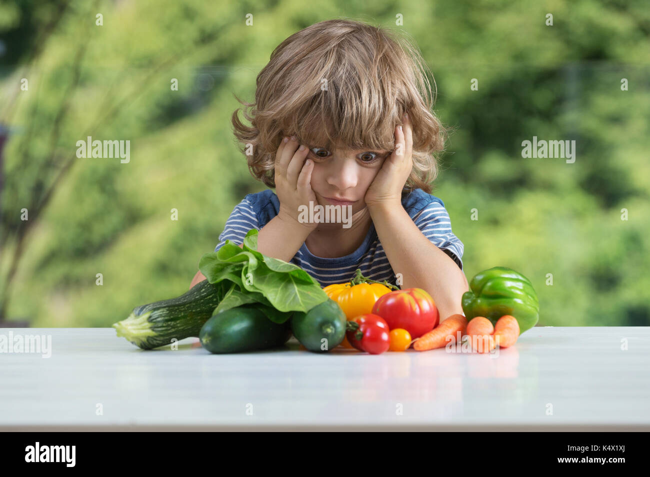 Cute little boy am Tisch sitzen, unglücklich mit seinem Gemüse essen, schlechte Essgewohnheiten, Ernährung und gesunde Ernährung Konzept Stockfoto