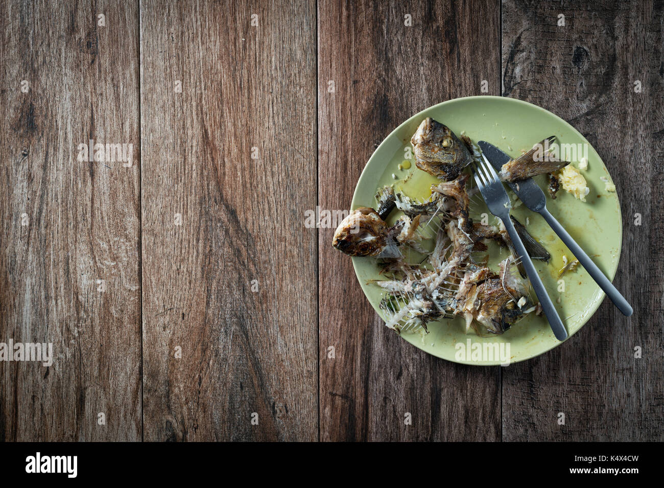Fisch auf dem Teller mit Messer und Gabel beiseite stellen. Essensreste, Hausmüll entsorgt. Einige negativen Raum. Stockfoto