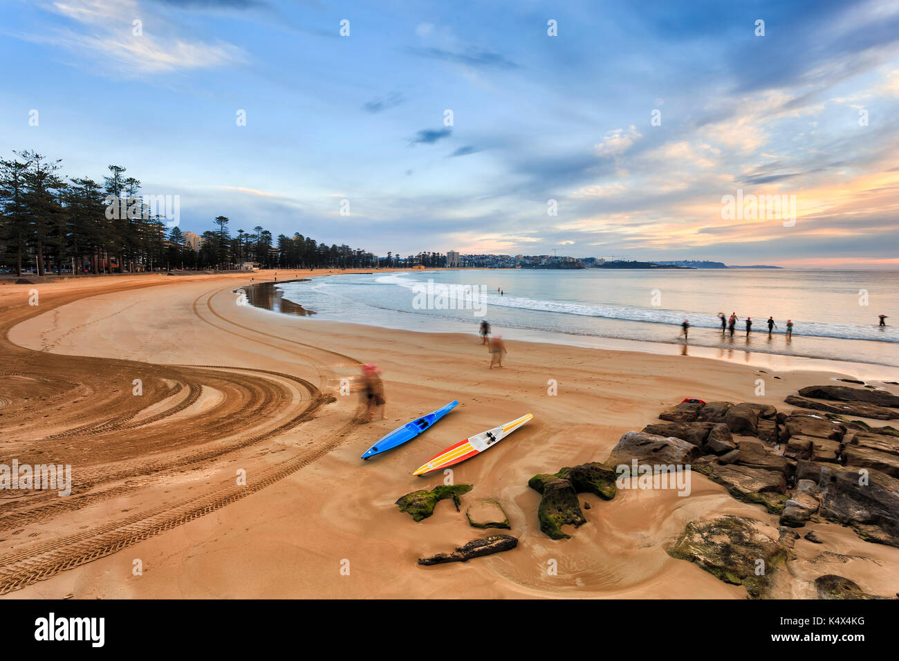 Früher Morgen Manly Strand bei Ebbe mit aktiven Menschen gehen zum Schwimmen und Laufen Kajaks über glatte Wasser des Pazifischen Ozeans aus australischen Küste in Sy Stockfoto