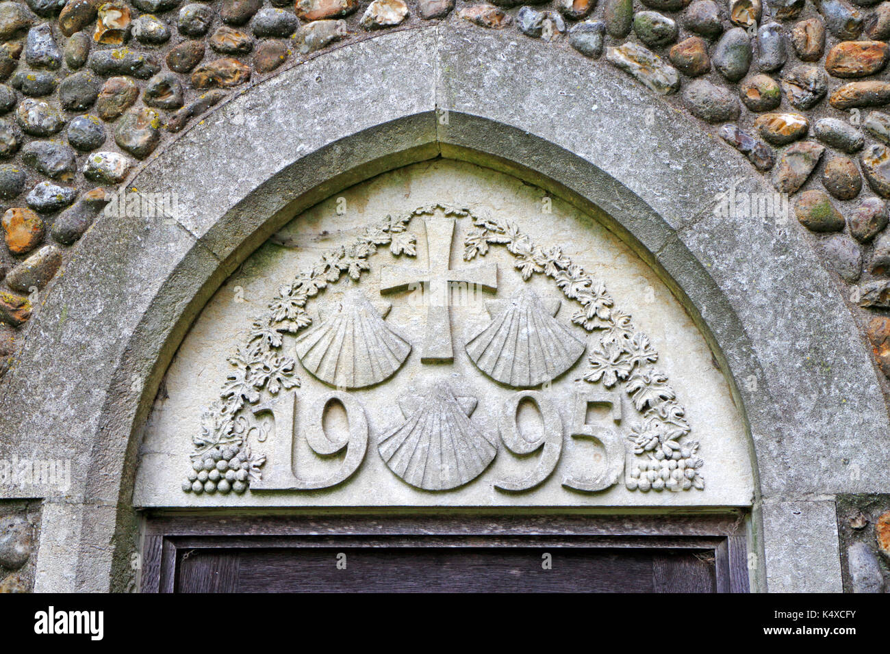 Modernes Mauerwerk mit den drei Jakobsmuscheln Symbol des Hl. Jakobus in der Pfarrkirche von St. James an Southrepps, Norfolk, England, UK. Stockfoto