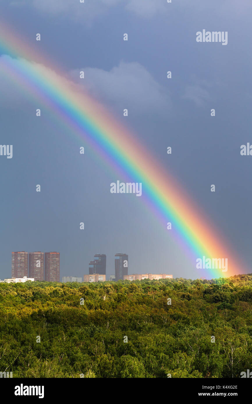 Rainbow im grauen Himmel über der Stadt Moskau und grüne Bäume im Stadtpark Timiryazevskiy im sonnigen Tag Stockfoto
