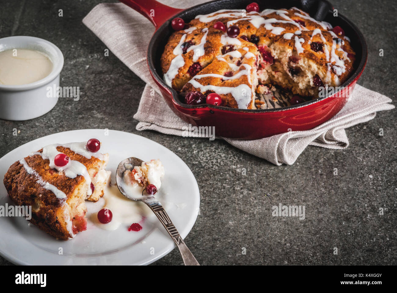 Britisches Englisch traditionelles Gebäck. Cookies Torte cranberry Scones  mit Orangenschalen, mit süßen weißen Glasur, in eine Pfanne geben und auf  einem Teller. Schwarz sto Stockfotografie - Alamy