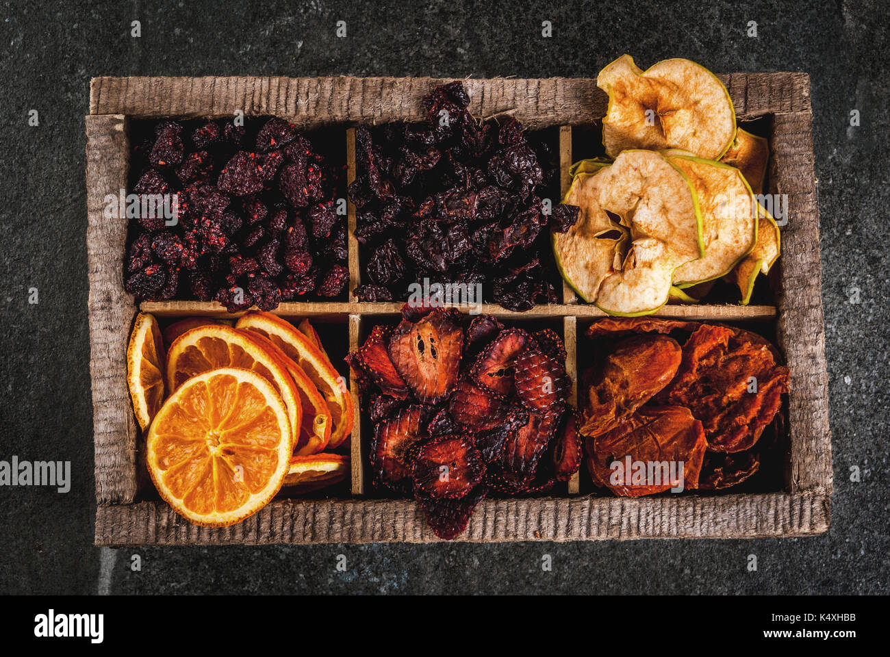 Hausgemachte getrockneten Beeren und Früchte, die Ernte für den Winter: Aprikosen, Äpfel, Erdbeeren, Himbeeren, Kirschen, Orangen. In alten Holzkiste, auf Schwarz Stockfoto