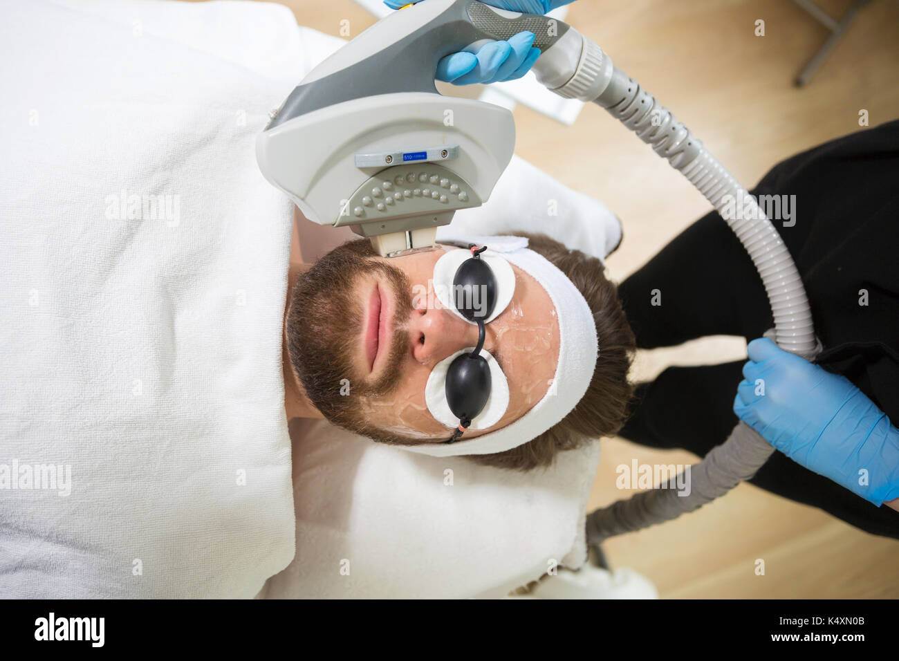 Mann an der Kosmetikerin, die im Verlauf der Laser Anti-Aging Therapie Stockfoto