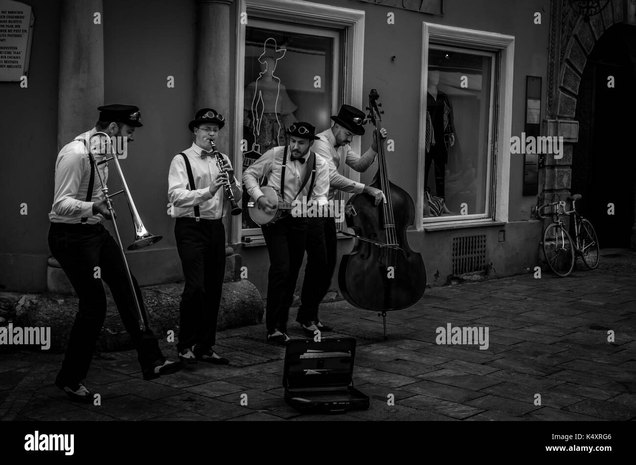 Straßenmusikanten spielen in einer schmalen Gasse in der Altstadt von Graz, Österreich, in Schwarz und Weiß. Stockfoto