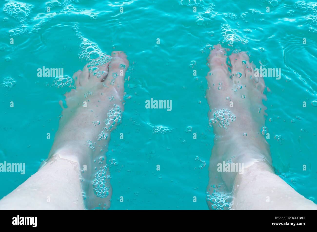 Beine in der warmen blauen Wasser des Swimmingpools. Sommer Urlaub. Stockfoto