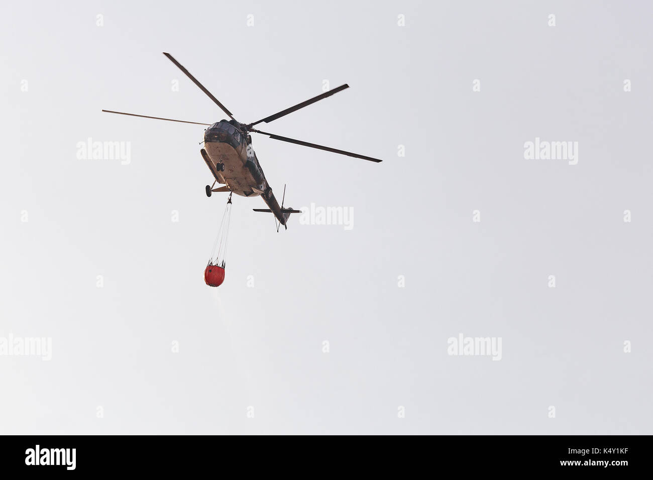 Feuerwehrmann Heli im Flug einen Wassereimer Stockfoto