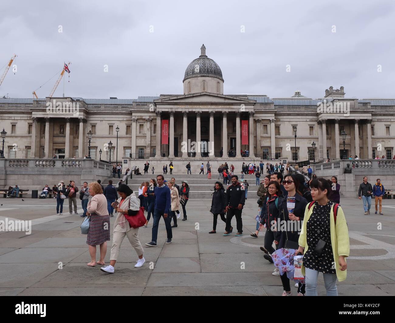 Menschen gehen vor der National Gallery, Trafalgar Square, London, UK. Stockfoto