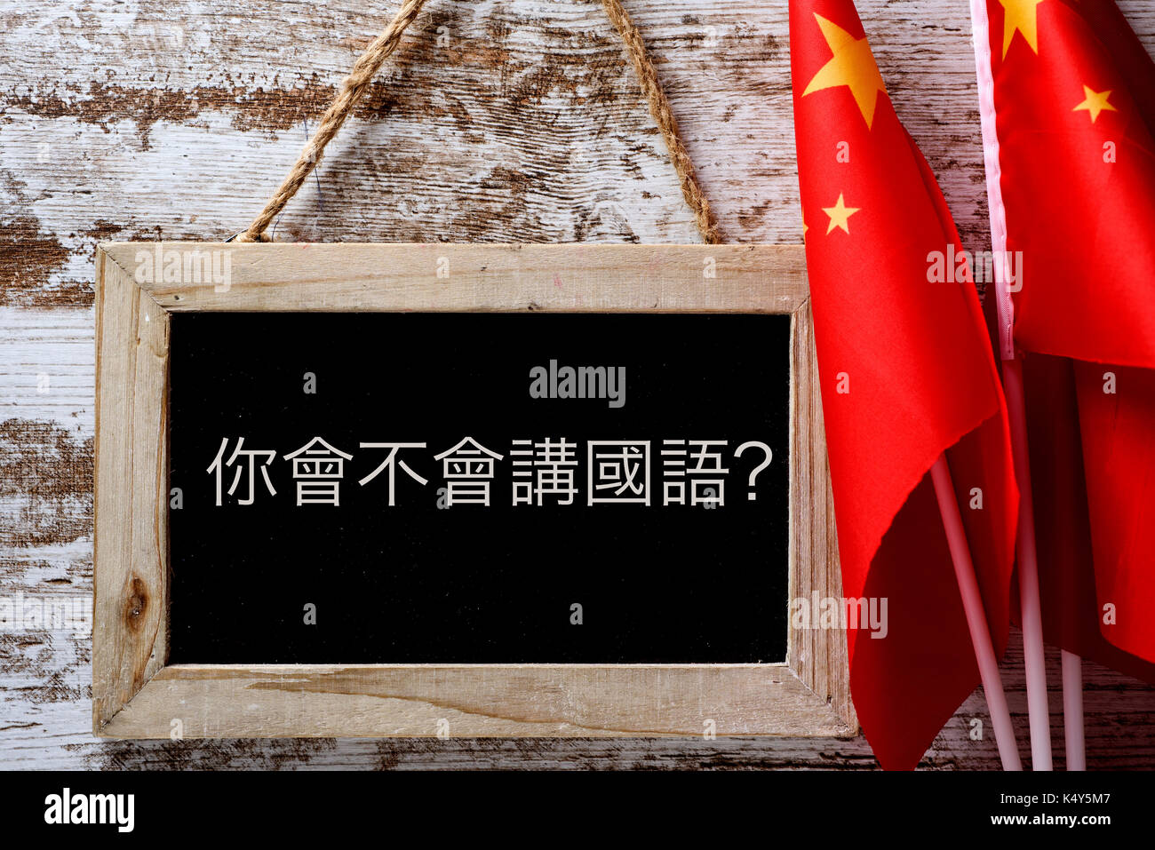 Eine hölzerne - schiefertafel mit der Frage formuliert haben Sie Chinesisch sprechen? In Chinesisch geschrieben, und einige Fahnen von China gegen einen rustikalen Holzmöbeln Hintergrund Stockfoto