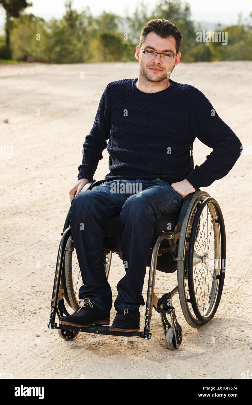 Junge behinderte Menschen im Rollstuhl Lächeln außerhalb. Stockfoto