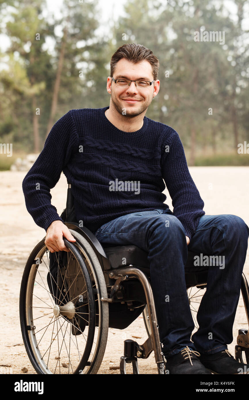 Junge behinderte Menschen im Rollstuhl Lächeln außerhalb. Stockfoto