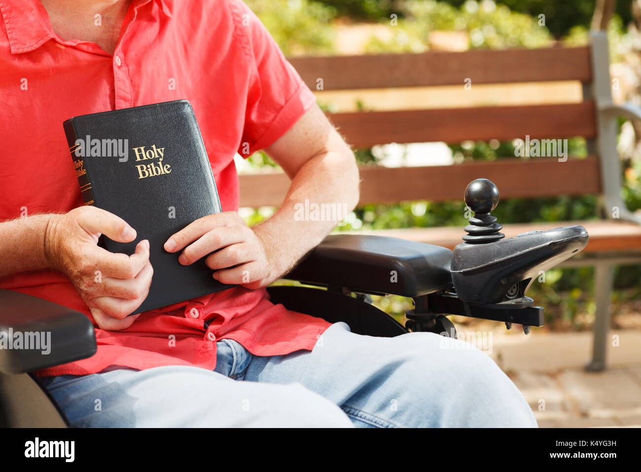 Bibel in den Händen von behinderten Menschen im Rollstuhl. Stockfoto