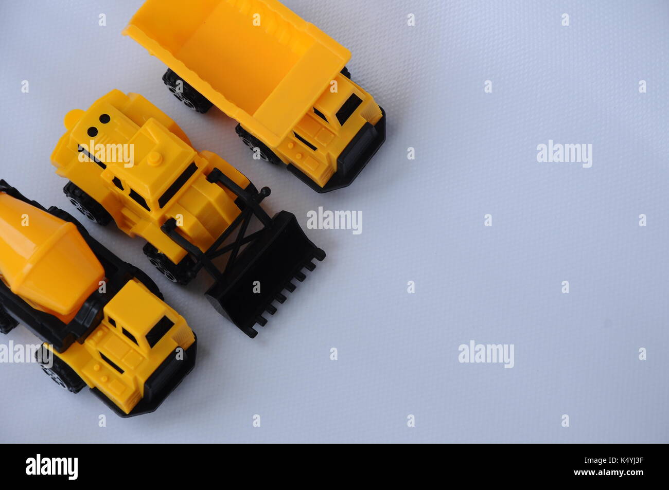 Gruppe von kleinen schwere Baumaschine Spielzeug, Lkw, Bulldozer und Betonmischer. Alle aus Kunststoff auf weißem Hintergrund. Stockfoto