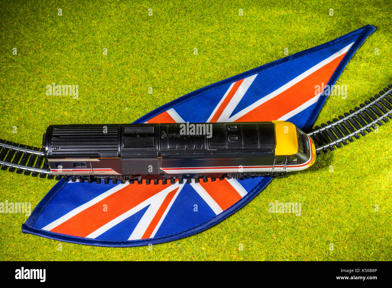 Ein Modell der Bahn und Schiene auf Union Jack Farben, von einer Wiese umgeben, auf das allgemeine Konzept der britischen Zug reisen. Stockfoto