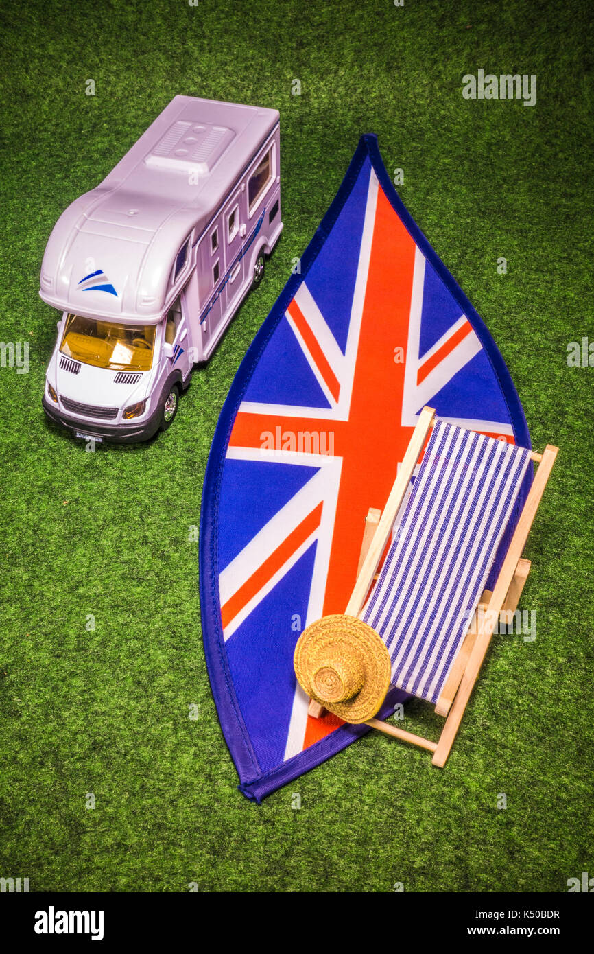 Ein Modell Reisemobil, Liegestuhl und Strohhut, auf Union Jack Farben. Konzept einer britischen Urlaub, Reise oder Urlaub Urlaub in einem Wohnmobil. Stockfoto