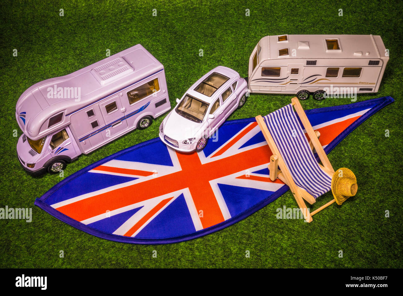 Ein Modell Wohnmobil, Auto mit Wohnwagen, Liegestuhl und Strohhut, auf Union Jack Farben. Konzept einer britischen Reisemobil oder Angaben zum Urlaub oder Tour. Stockfoto