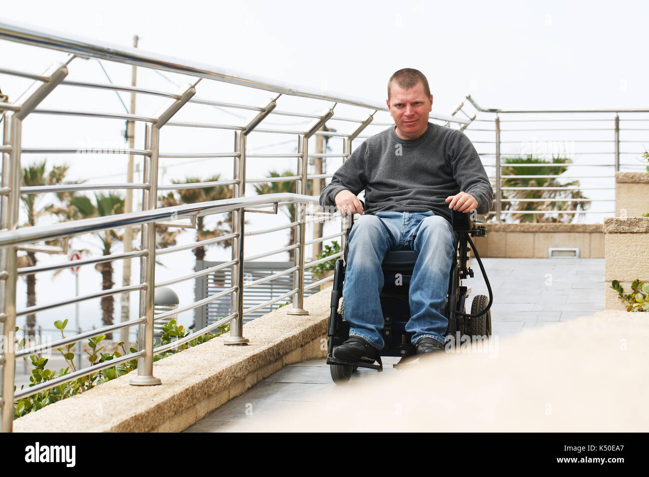 Mann im Rollstuhl sitzt in der Nähe der Geländer Stockfoto