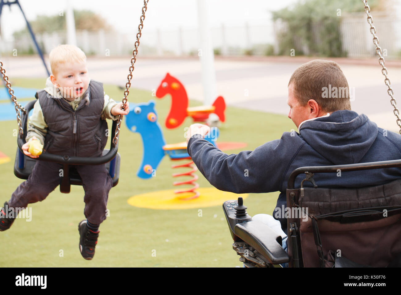 Behinderten Vater spielen mit seinem kleinen Sohn auf dem Spielplatz. Stockfoto