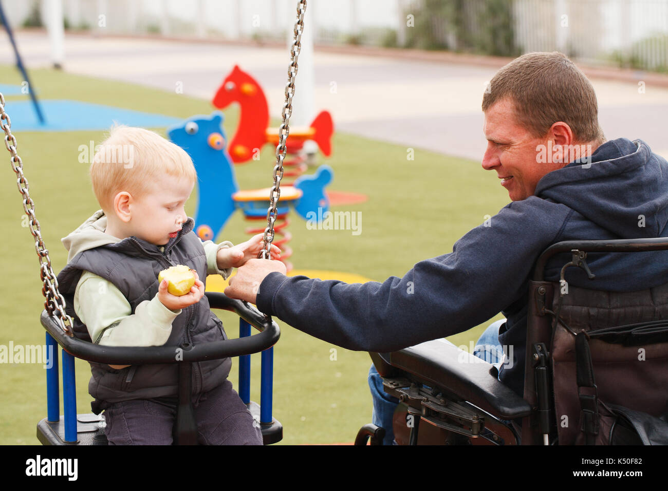 Behinderten Vater spielen mit seinem kleinen Sohn auf dem Spielplatz Stockfoto