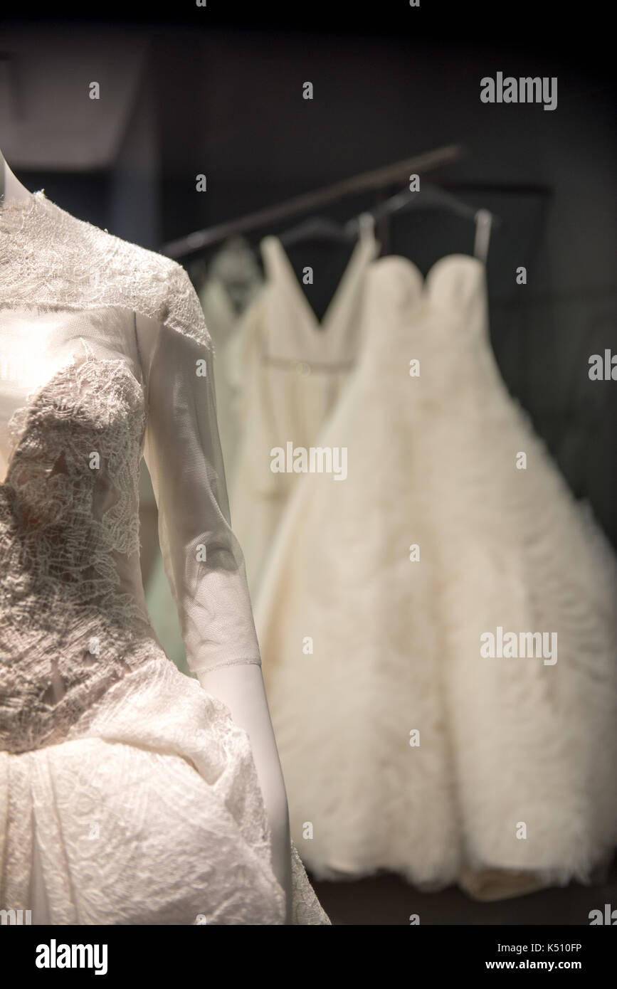 Dekorativ besticktes Oberteil, das von einem weißen Ballkleid oder Brautkleid leuchtet auf dem Display in einem abgedunkelten Raum Stockfoto
