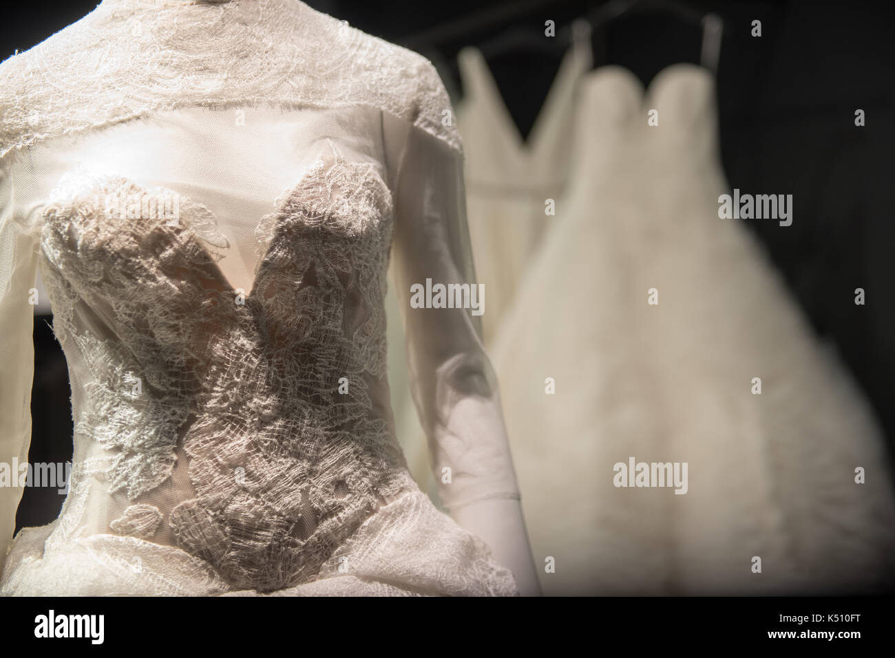 Dekorativ besticktes Oberteil, das von einem weißen Ballkleid oder Brautkleid leuchtet auf dem Display in einem abgedunkelten Raum Stockfoto