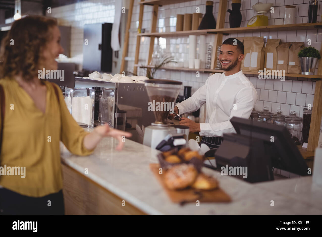 Lächelnd Kellner an weiblichen Kunden stehen an der Theke im Café suchen Stockfoto
