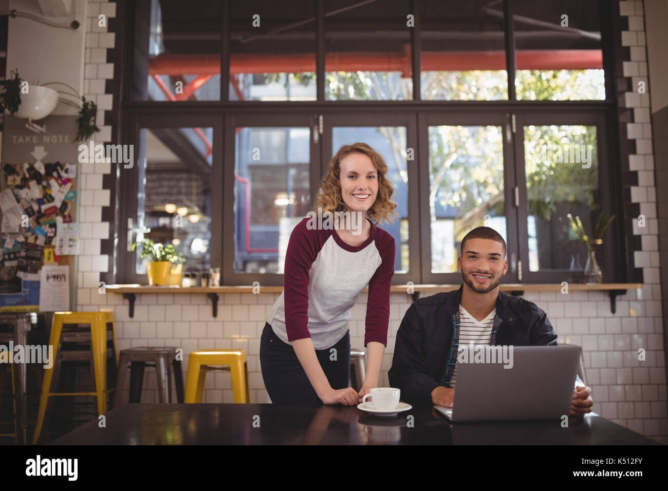 Portrait von lächelnden Mann und Frau mit Laptop am Tisch im Café Stockfoto