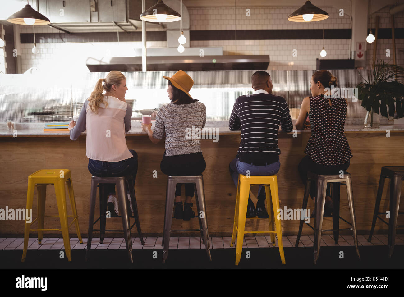 Ansicht der Rückseite des Freunde sitzen auf Hocker an der Theke im Café Stockfoto