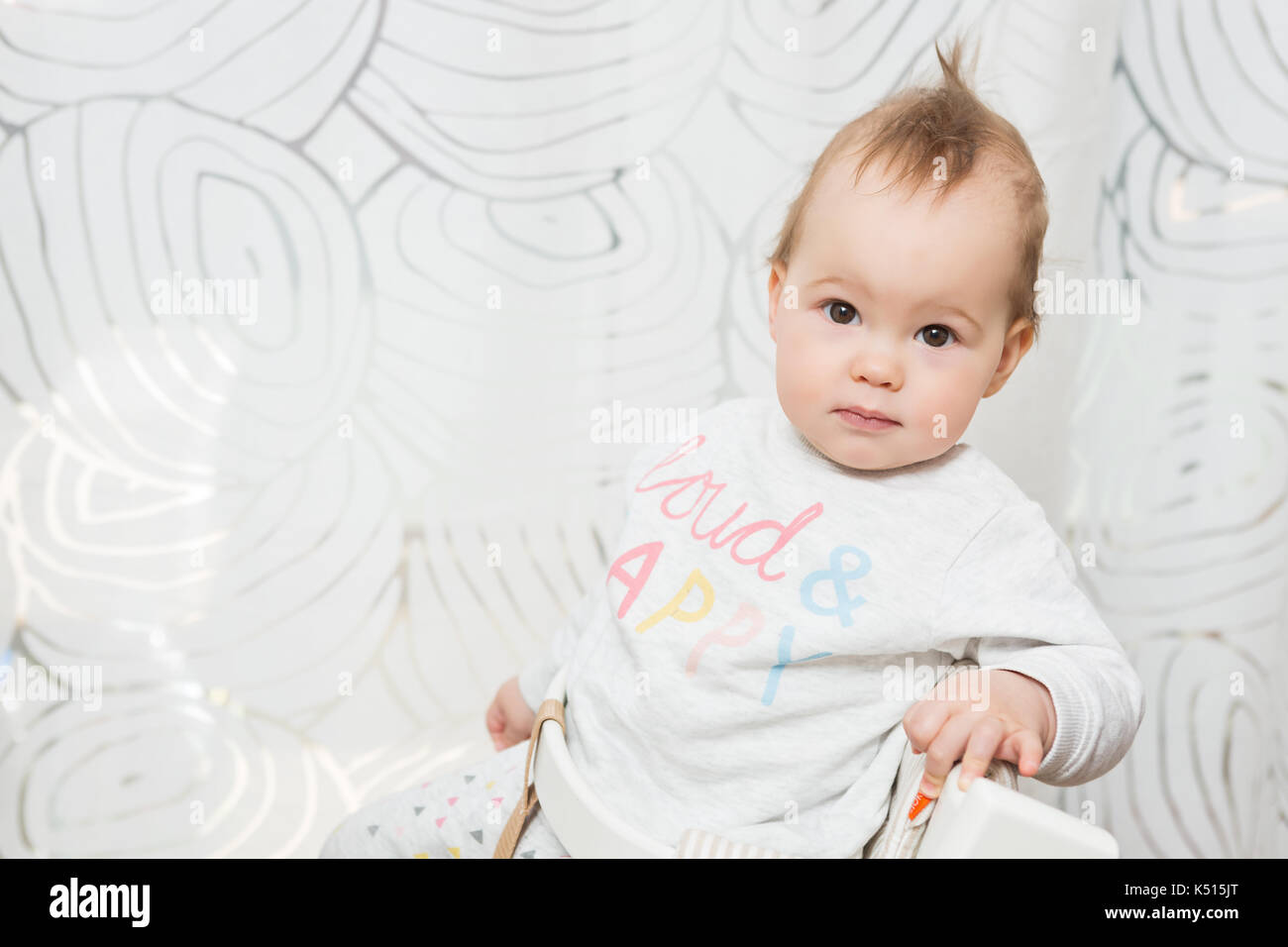 Elf Monate alten Baby Mädchen in einem Hocker, lustige Gesichter in die Kamera sitzen Stockfoto