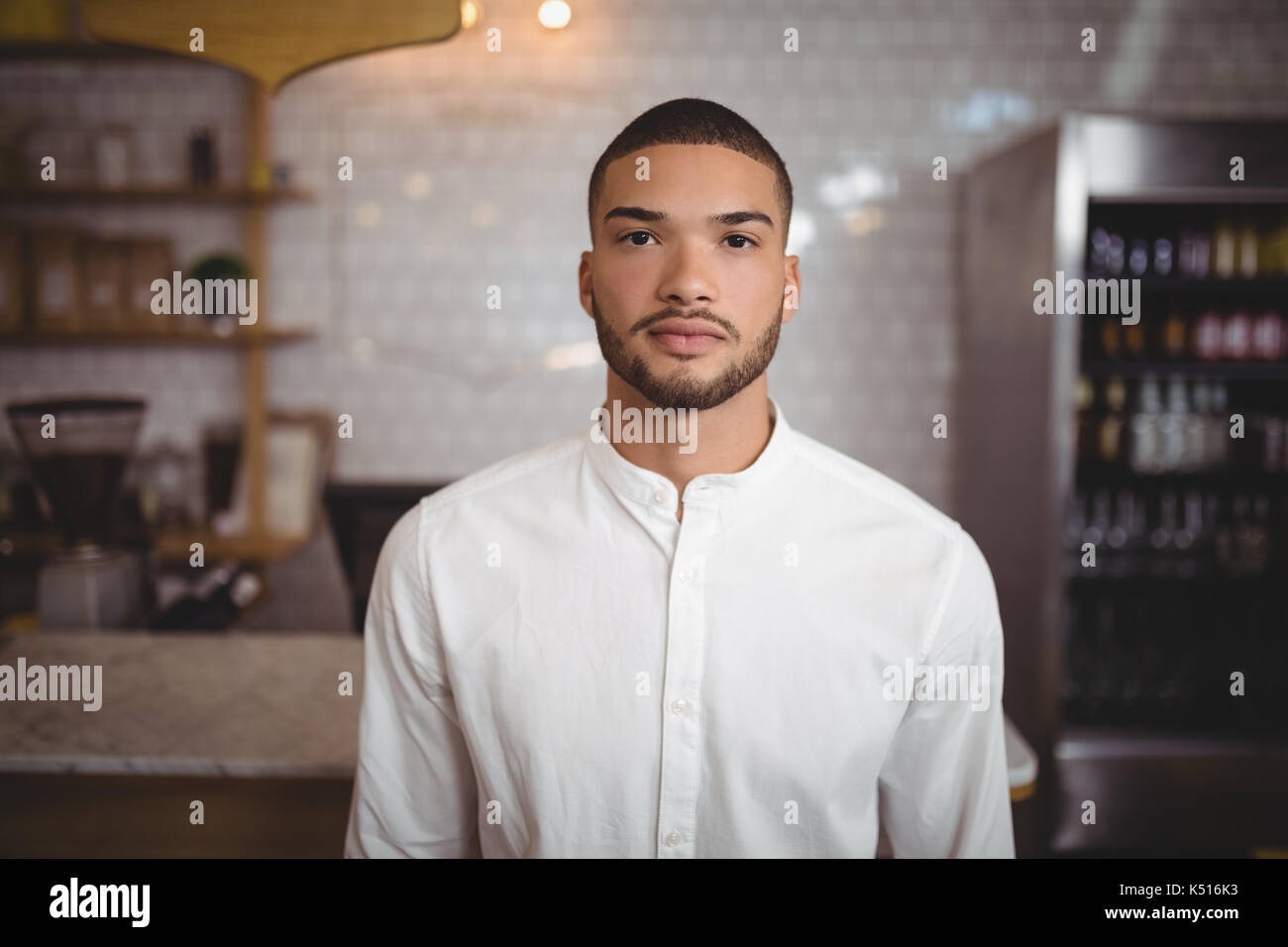 Portrait von selbstbewussten jungen Mann gegen die Wand im Coffee shop Stand Stockfoto