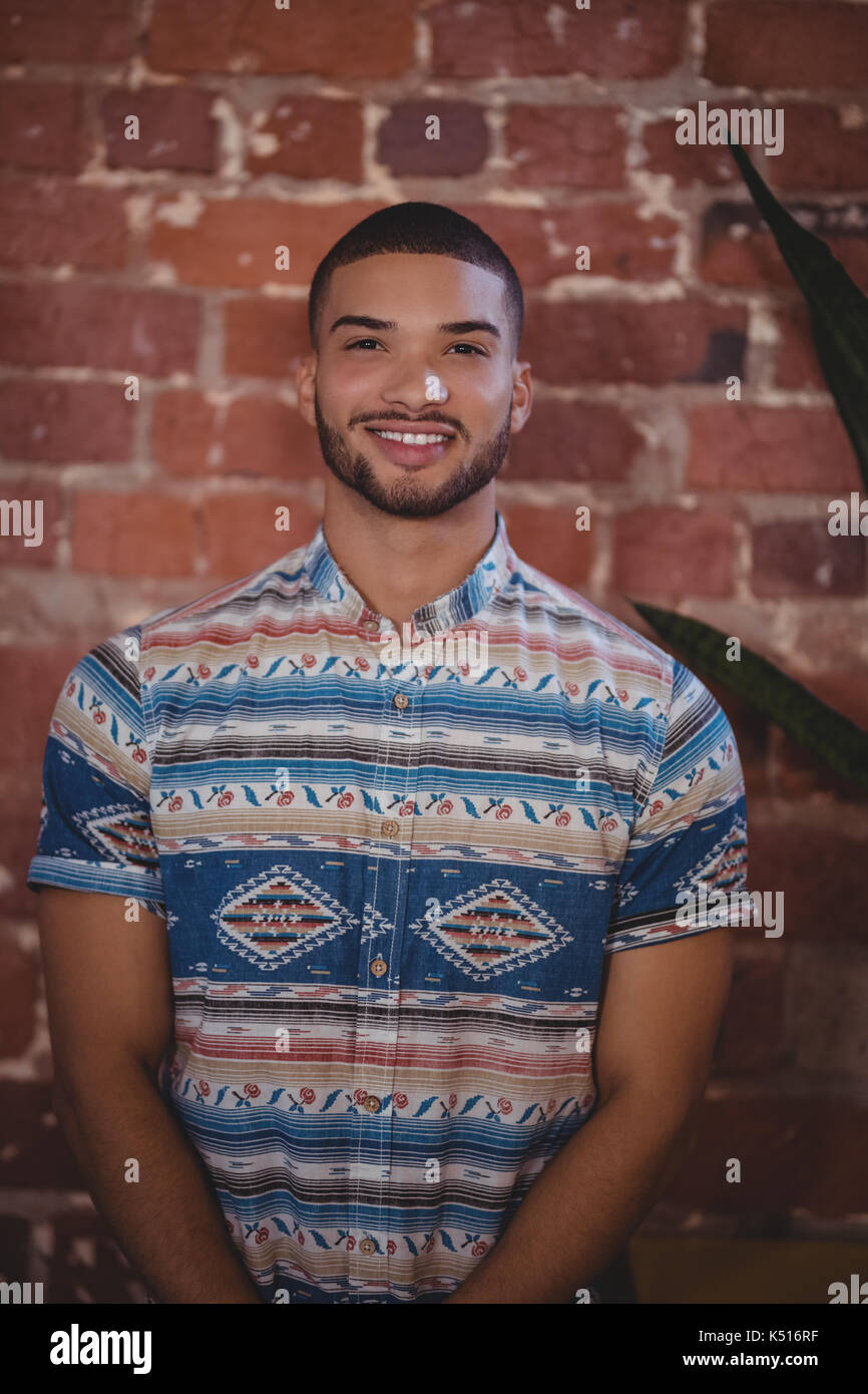 Portrait von lächelnden jungen männlichen Kunden steht gegen die Mauer im Coffee Shop Stockfoto