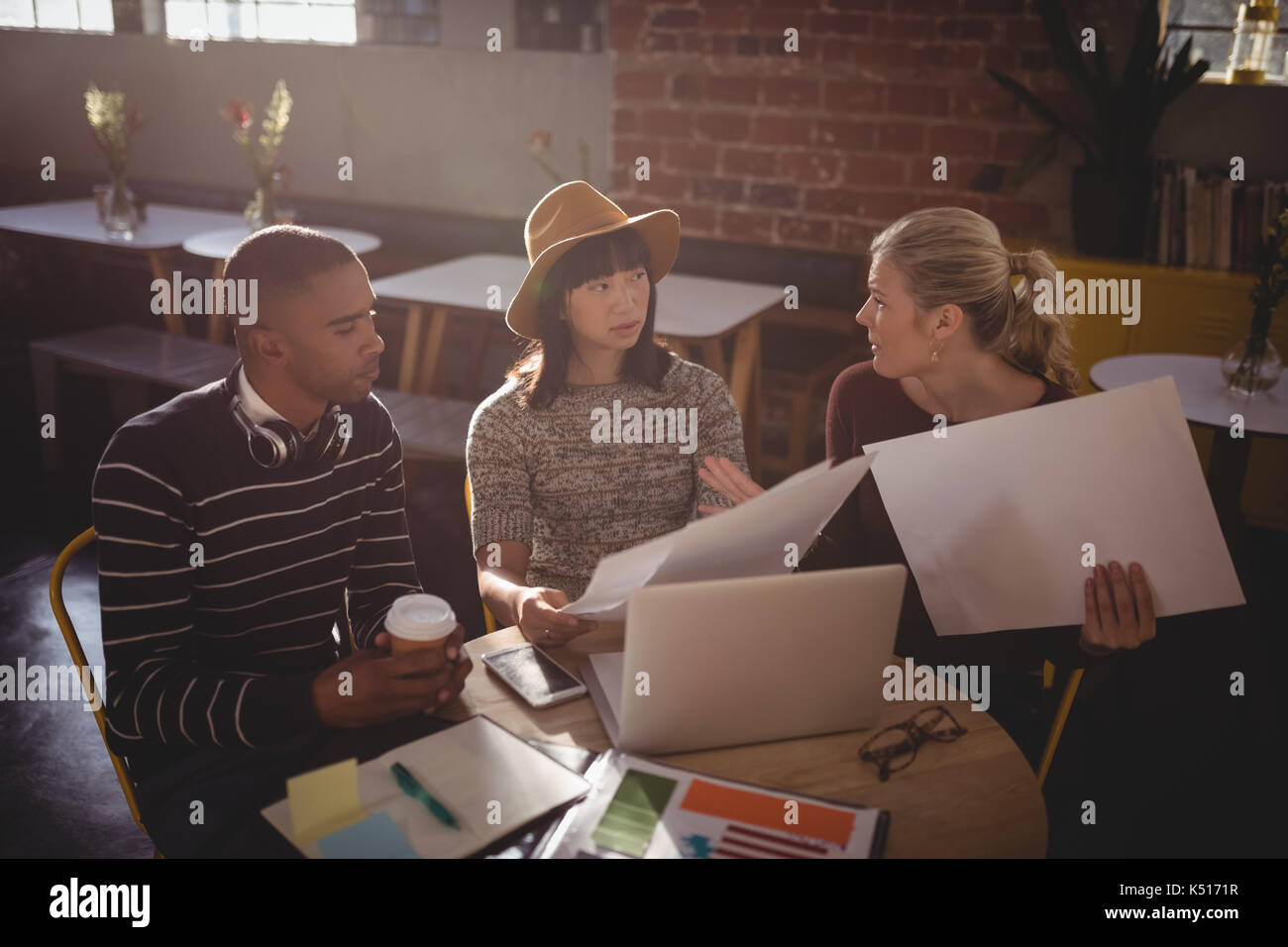 Hohe Betrachtungswinkel von jungen kreativen Team sitzt mit Laptop und Papiere im Coffee Shop Stockfoto