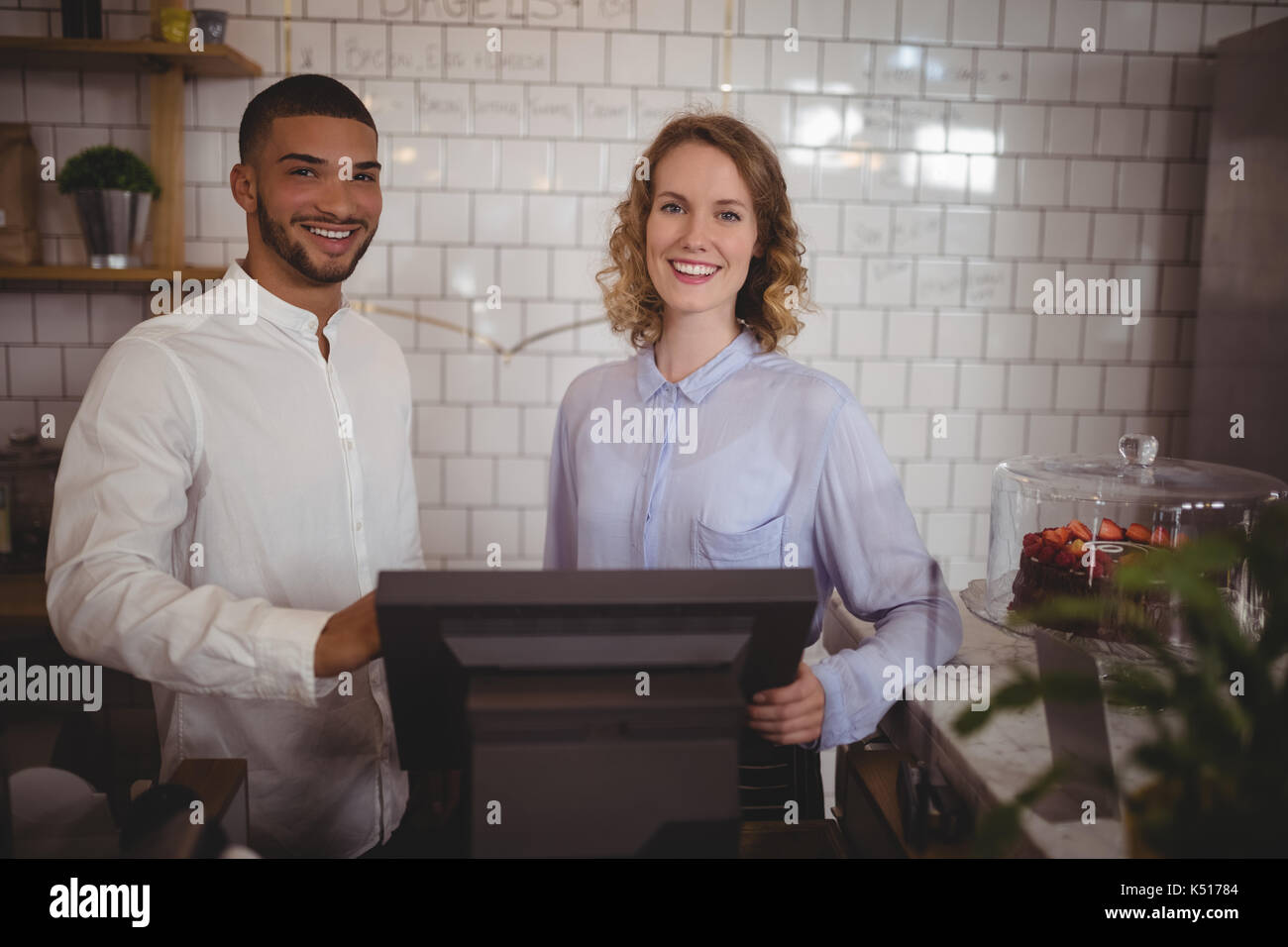 Portrait von lächelnden Kellnerin und männlichen Eigentümer stehen Computer. Im Café Stockfoto