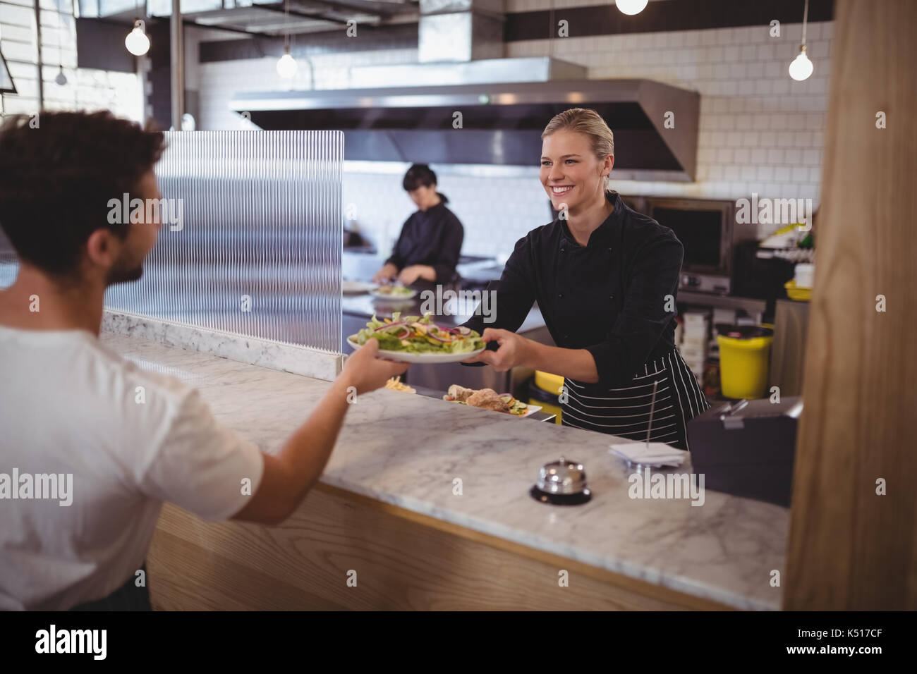 Lächelnd weibliche Küchenchef mit frischen griechischen Salat an Coffee shop Kellner Stockfoto