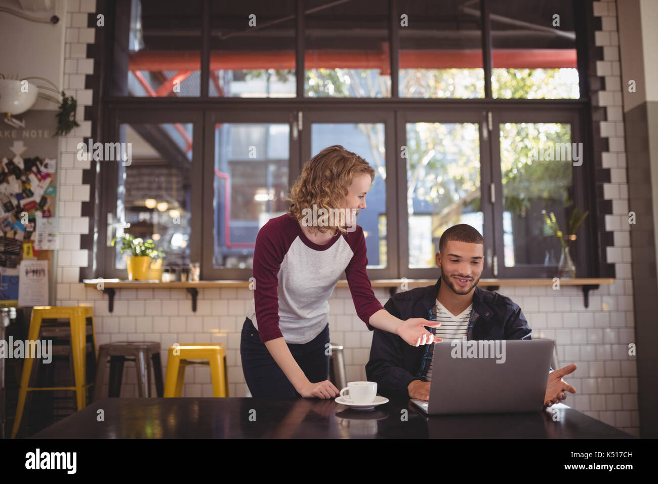 Junger Mann und Frau gestikulierend am Laptop im Coffee Shop Stockfoto