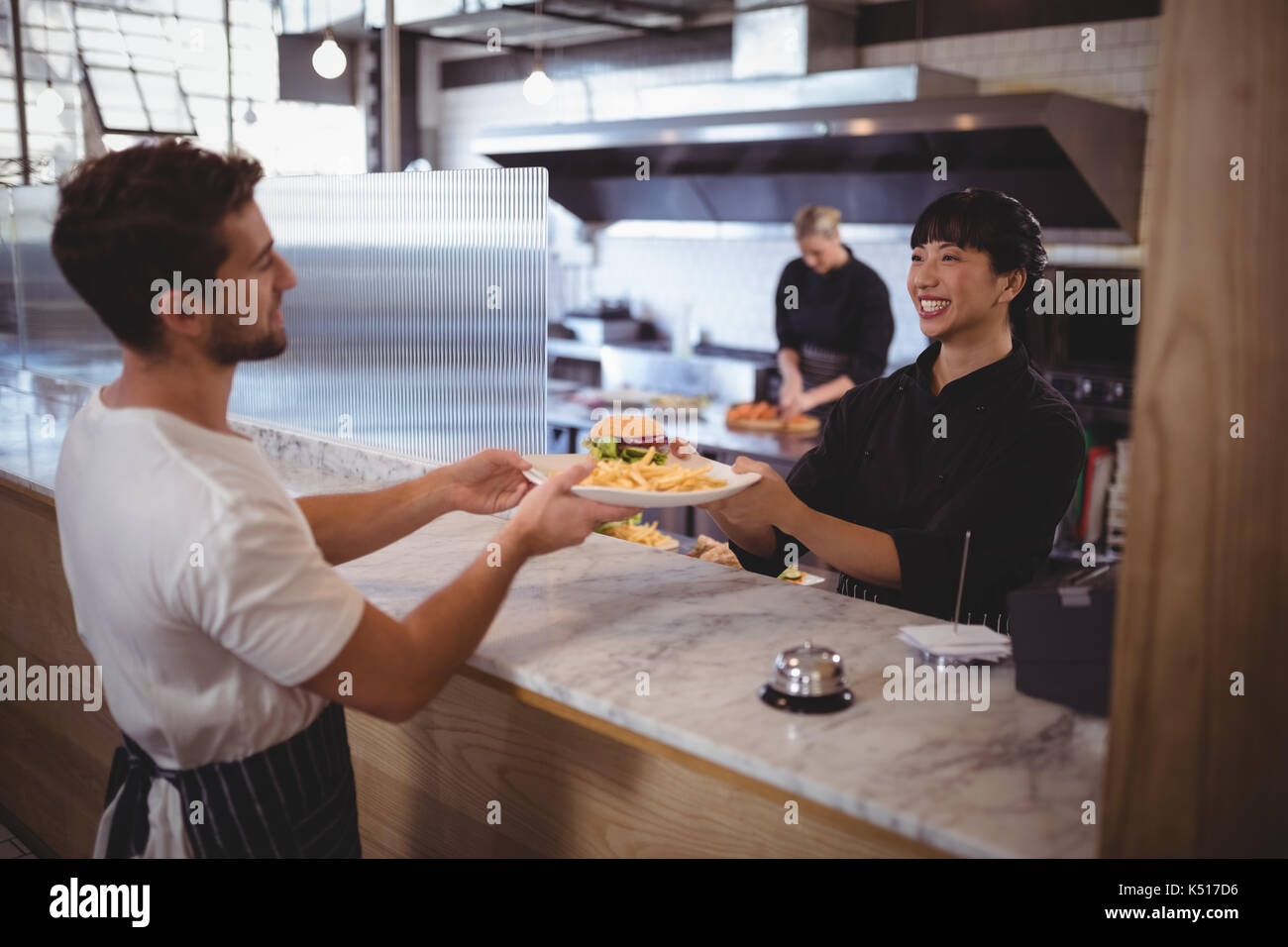 Lächelnden jungen Köchin, Burger und Pommes frites bei Coffee shop Kellner Stockfoto
