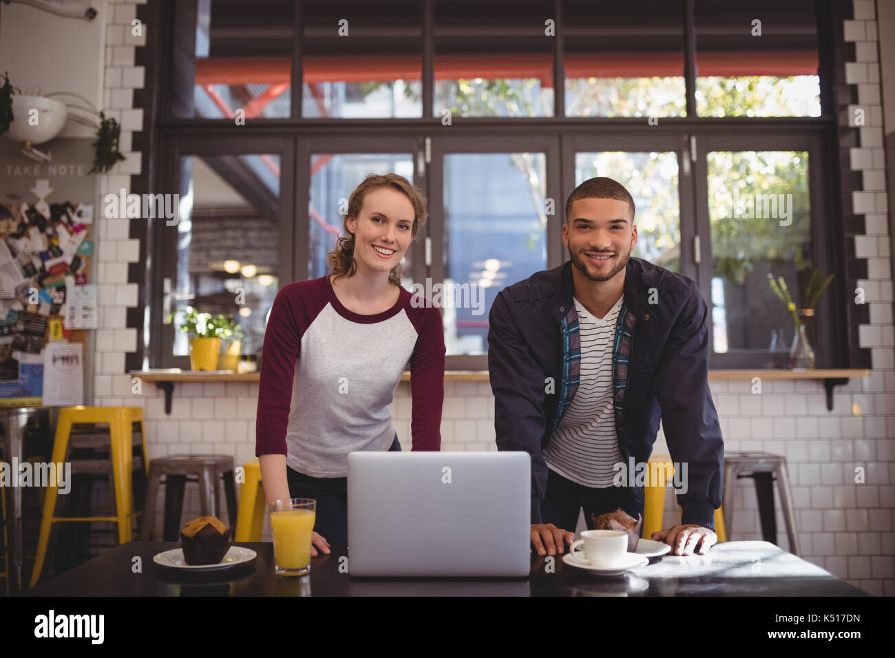 Portrait von lächelnden jungen Mann und Frau mit Laptop auf dem Tisch im Café Stockfoto