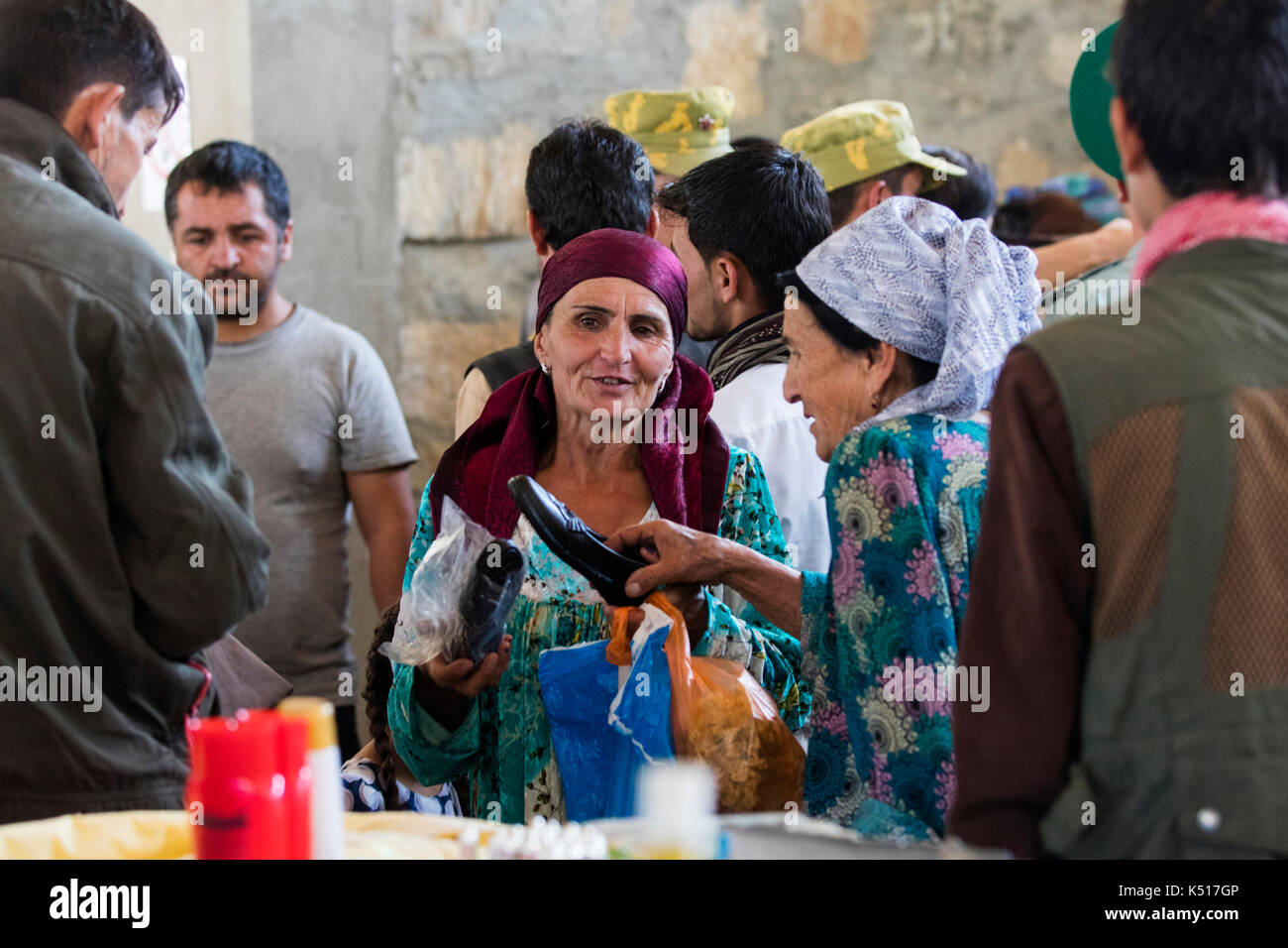 Afghanische Frau verkauft Schuhe auf dem Samstagsmarkt / Tadschikisch-afghanische Freundschaftsmarkt in Khorugh, Hauptstadt von Gorno-Badakhshan in Tadschikistan Stockfoto