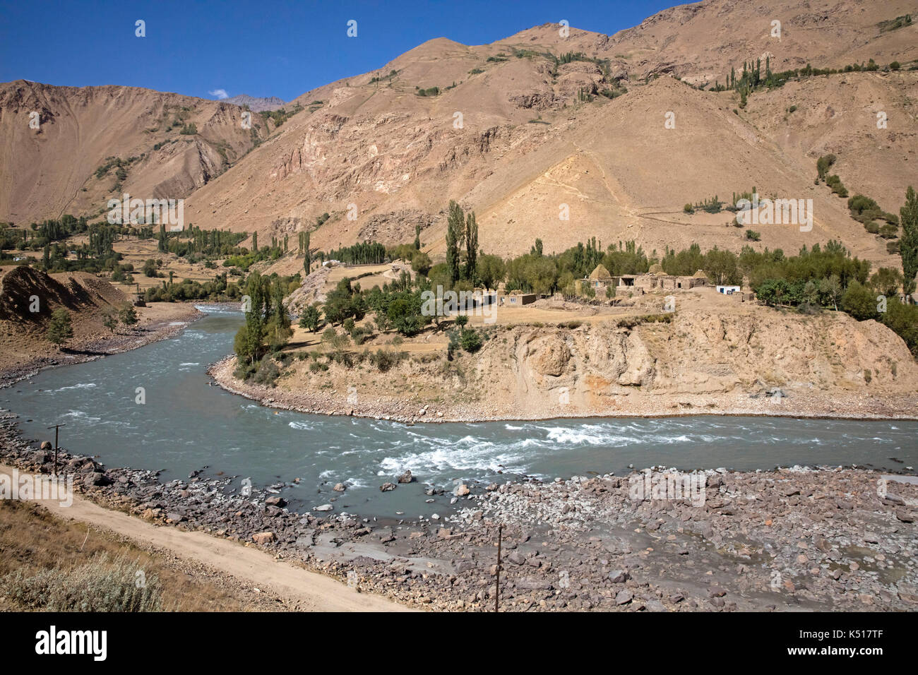 Kleines afghanisches Dorf und der Pamir Highway / M41 entlang des Pamir Flusses, bildet die Grenze zwischen Tadschikistan und Afghanistan Stockfoto