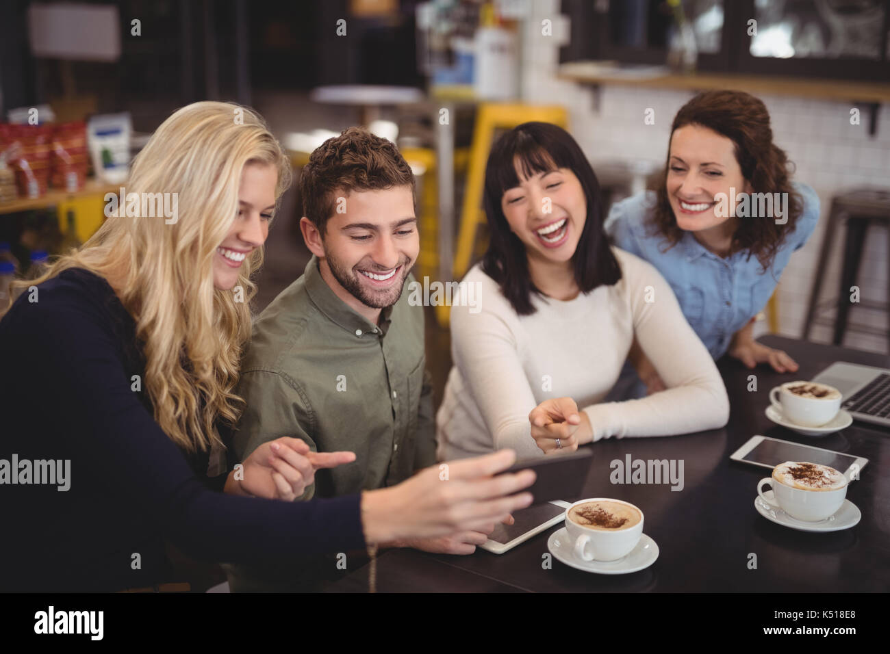 Fröhliche Freunde mit digitalen Tablet beim Sitzen am Tisch im Café Stockfoto
