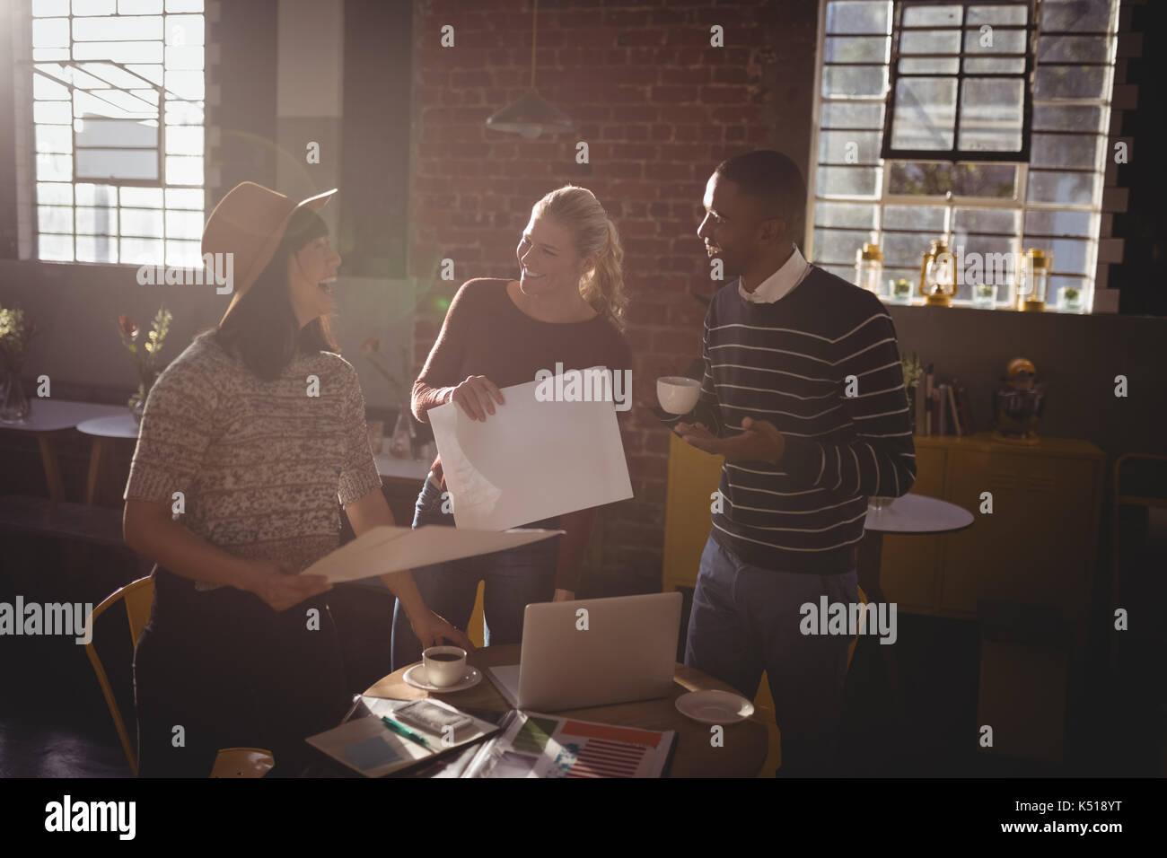 Fröhliche kreatives Team stehen mit Papieren im Coffee Shop Stockfoto
