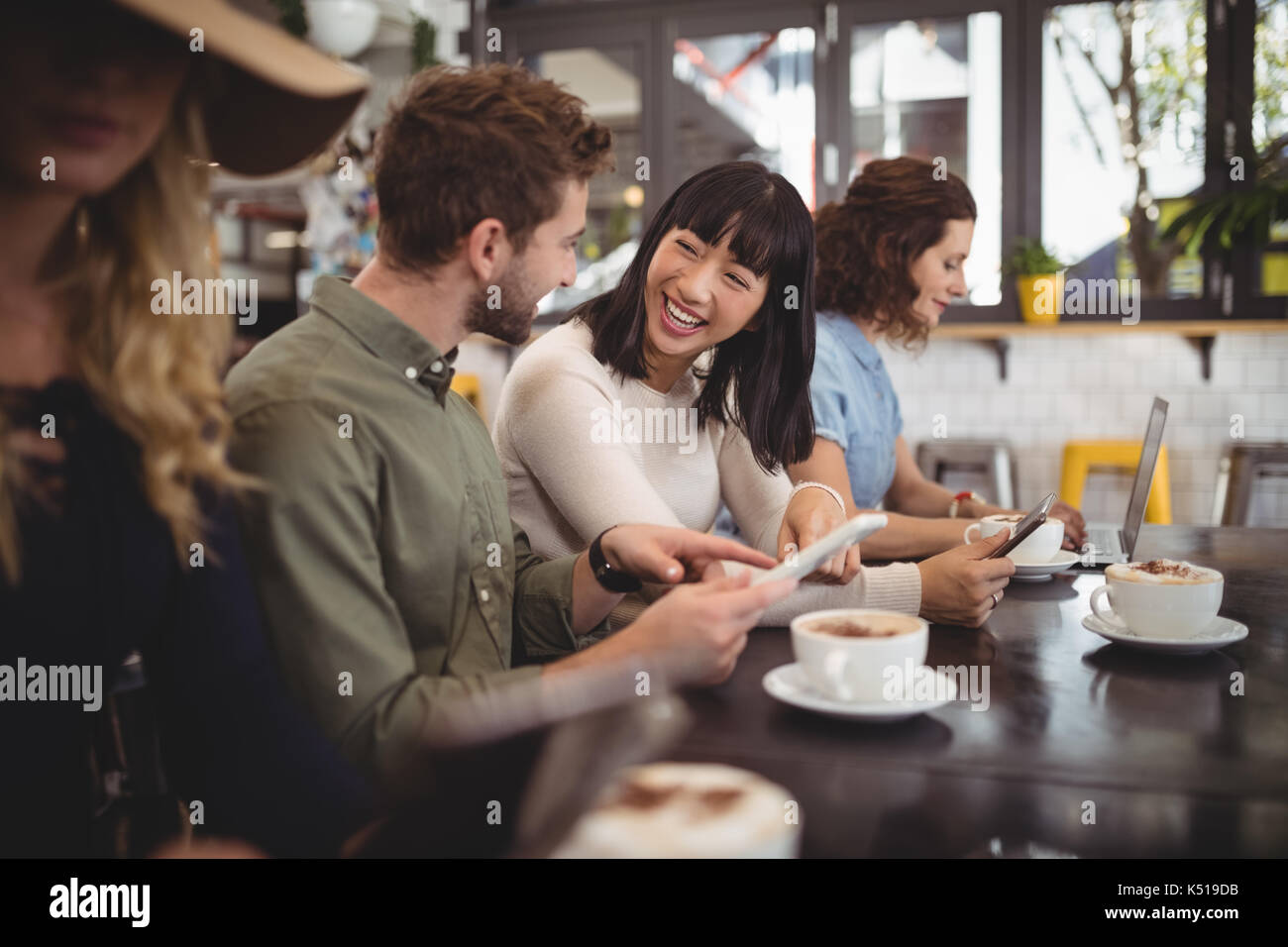 Lächelnden jungen Freunde sprechen, beim Sitzen am Tisch im Cafe Stockfoto