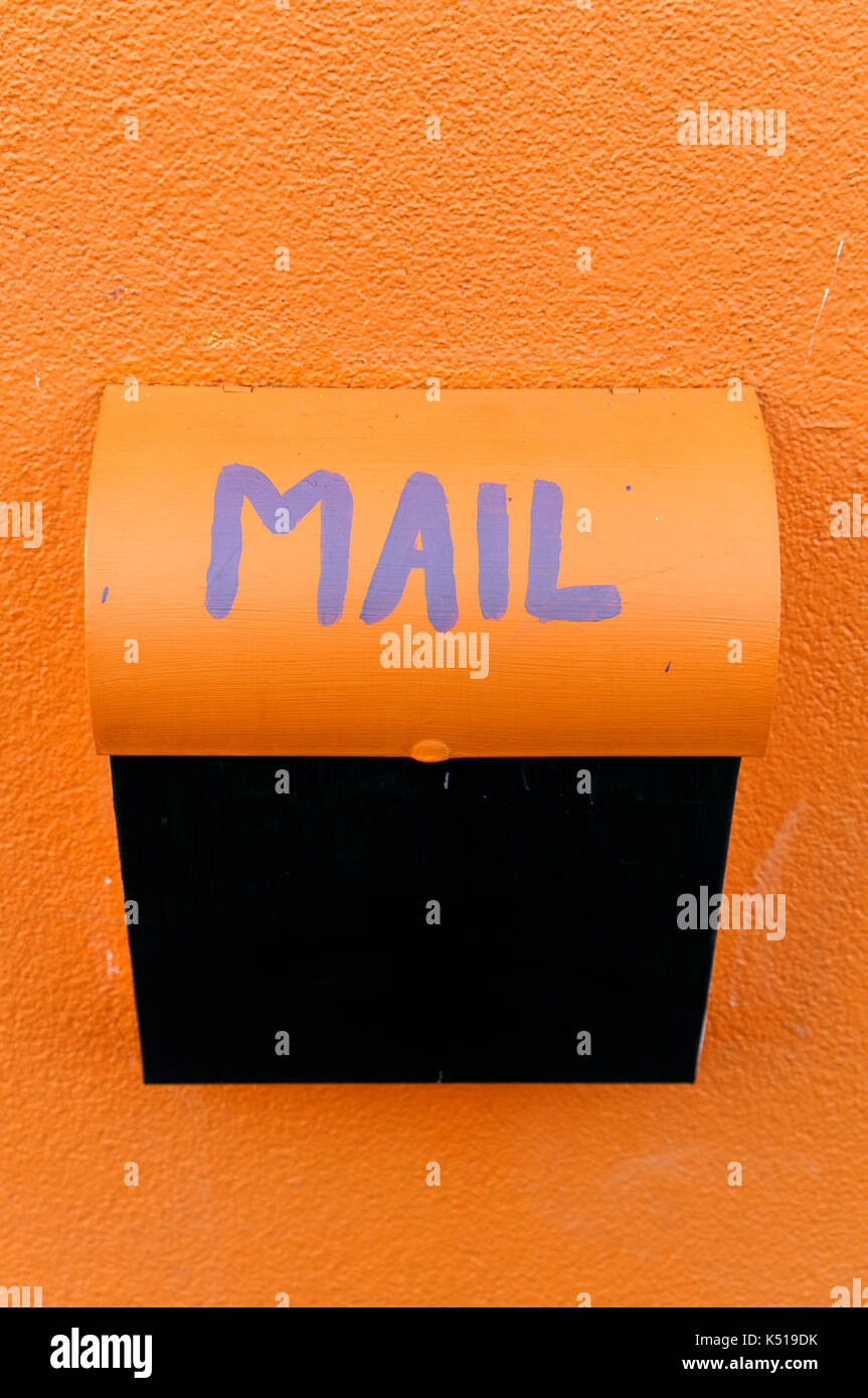 Metall orange und schwarz-Mailbox auf einem orange Stuck Wand befestigt Stockfoto