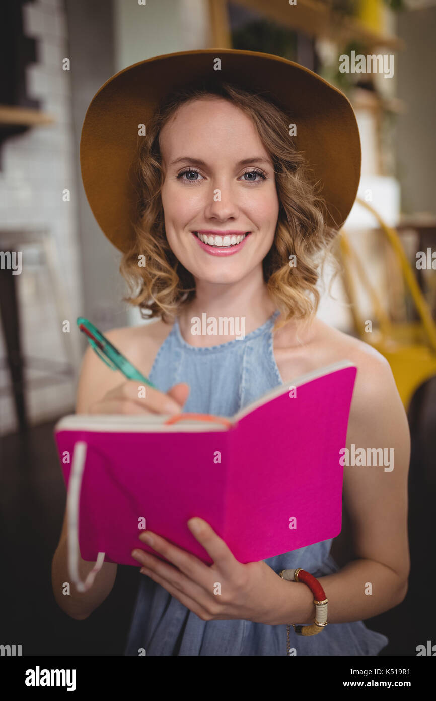 Portrait von lächelnden jungen Frau mit rosa Molkerei mit pen Coffee Shop Stockfoto