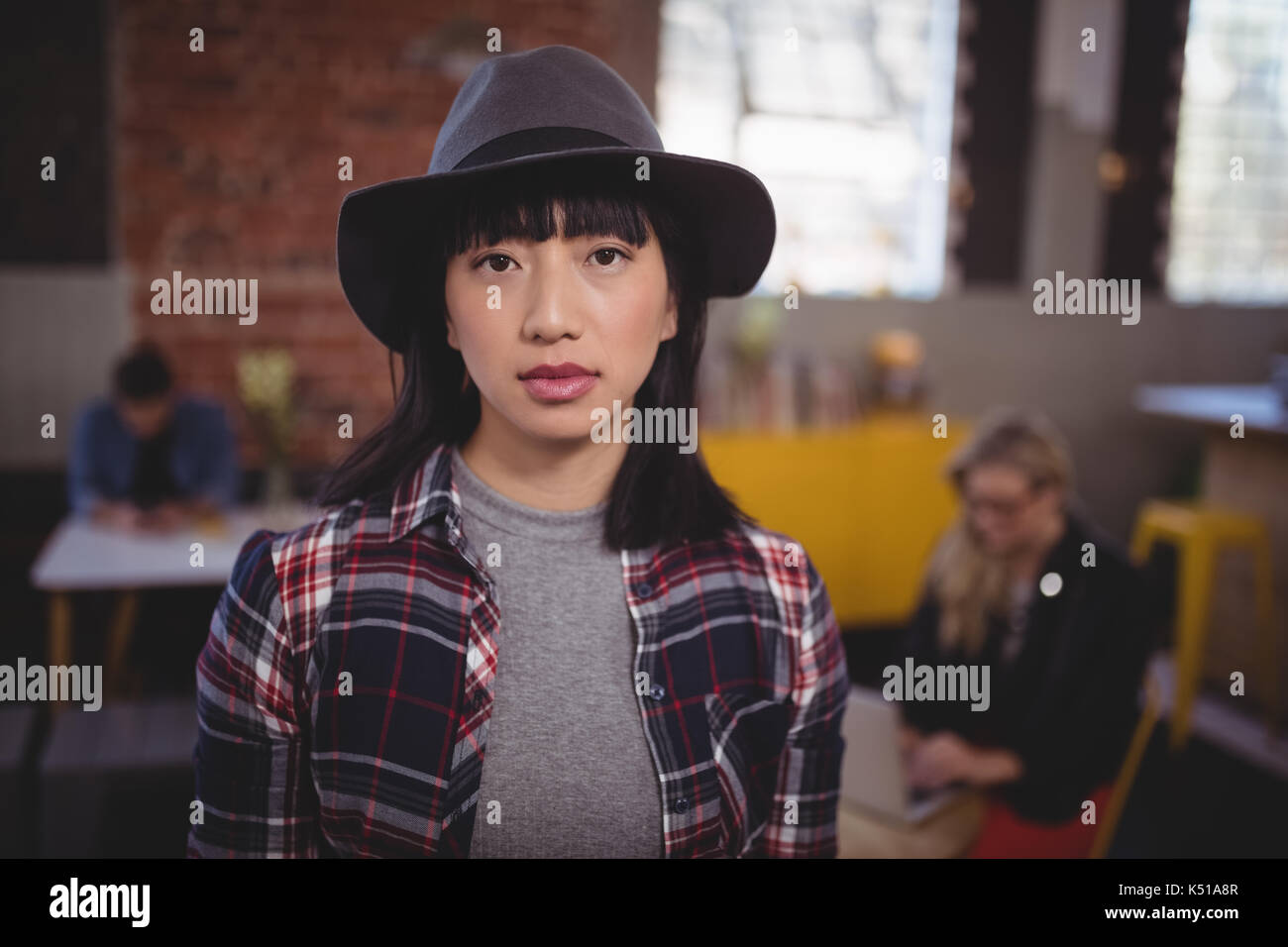 Portrait von selbstbewussten jungen Frau mit Hut, während Coffee Shop Stand Stockfoto
