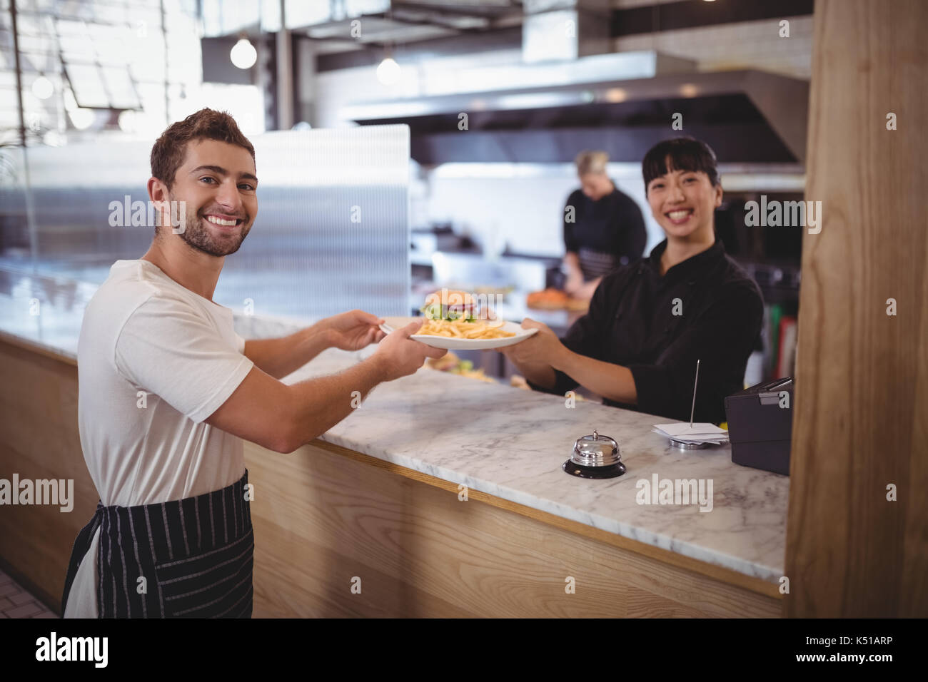 Portrait von lächelnden Frau Koch und Kellner, mit denen die Platte am Zähler in Coffee Shop Stockfoto